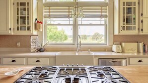 Una cocina con estufa a gas, un fregadero y una ventana con persianas.