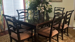 A dining room with a glass-top table surrounded by four chairs, a chandelier, and a floral arrangement. - Quaint Home With Dock on Lagoon - Walk to Beach (Hilton Head Island)