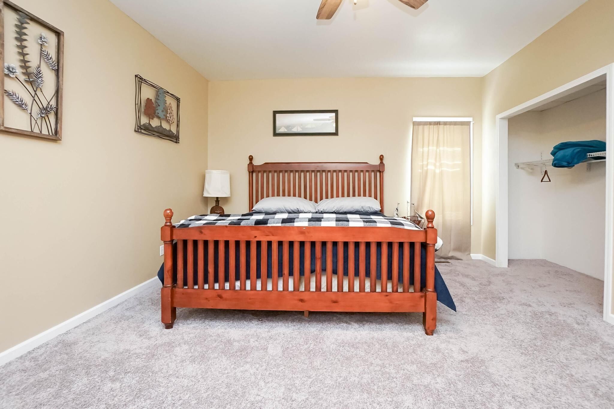 A bedroom with a wooden bed, beige walls, and a ceiling fan.