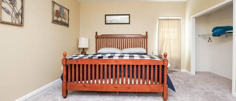 A bedroom with a wooden bed, beige walls, and a ceiling fan.