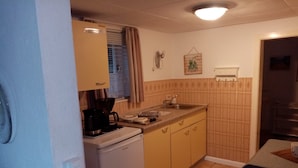A compact kitchen with a refrigerator, stove, sink, and a small dining area with a table.