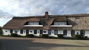 A traditional thatched-roof building with a white facade, multiple windows, and a sign indicating the year 1788.