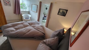 A bedroom with a bed, pillows, a chair, and a picture on the wall.