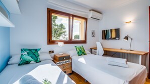 Une chambre avec deux lits, un bureau, une télévision et une fenêtre donnant sur la forêt.