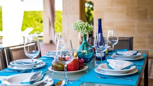 Une table dressée pour un repas, avec des nappes bleues, de la vaisselle transparente et un vase bleu contenant des fleurs blanches.