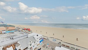 A beachside view with a boardwalk, buildings, and a sandy beach.