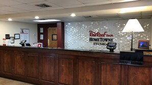 A reception desk with a digital kiosk, a Red Roof Inn sign, and a wall-mounted lamp. - HomeTowne Studios By Red Roof Augusta (Augusta)