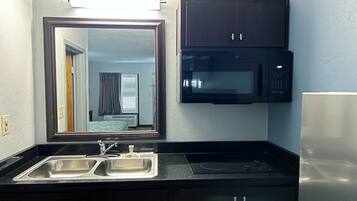 Une petite cuisine équipée comprenant un évier à deux bacs, un four à micro-ondes et un réfrigérateur.