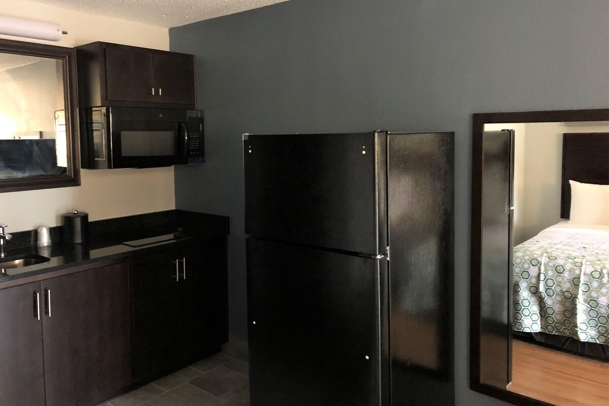 A compact kitchen with dark cabinetry, a microwave, and a refrigerator.