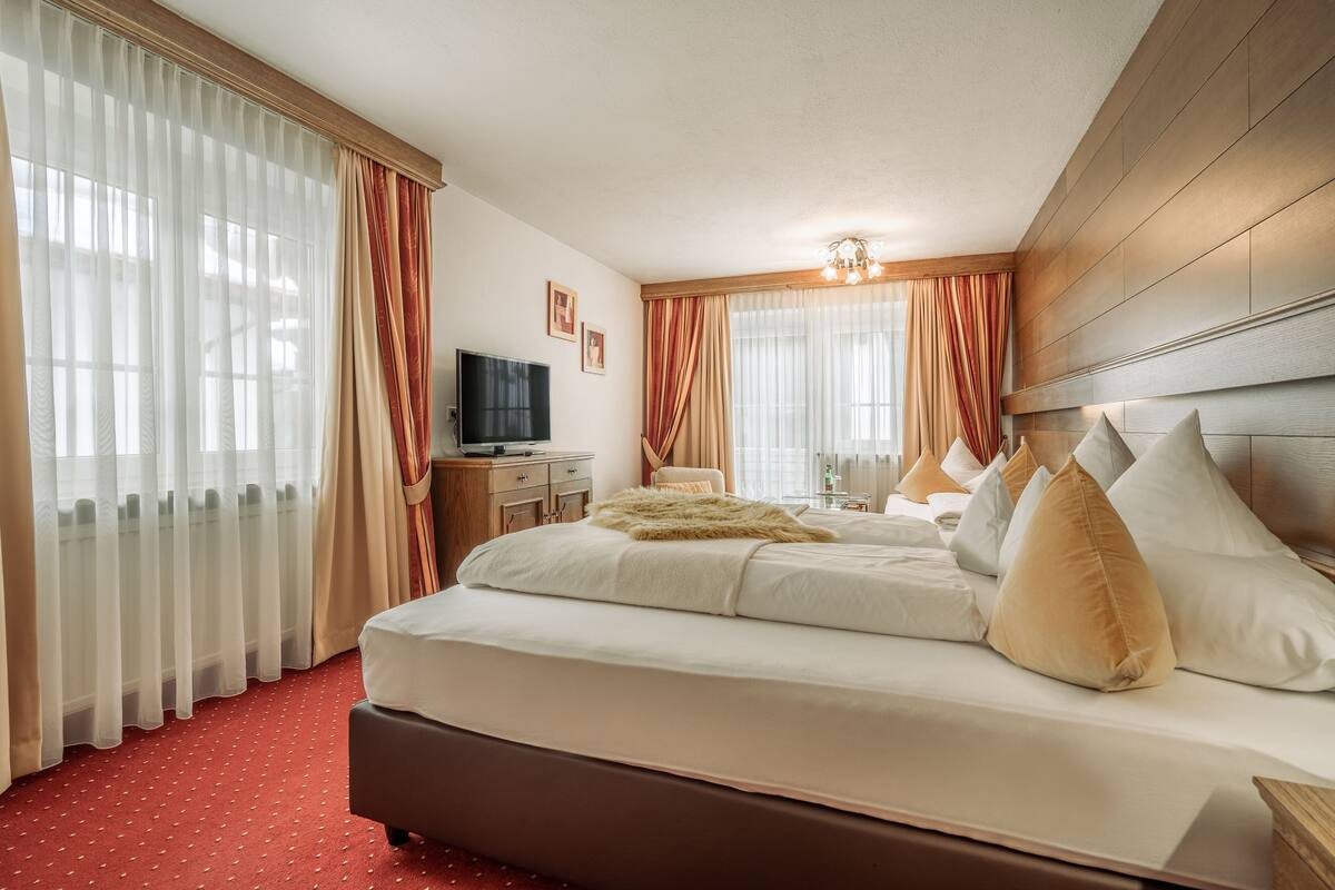 A hotel room with a large bed, a television, a desk, and a chair.