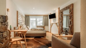 Ein Schlafzimmer mit einem Bett, einem Fernseher, einer Steinwand, einem Holztisch und einem großen Spiegel.