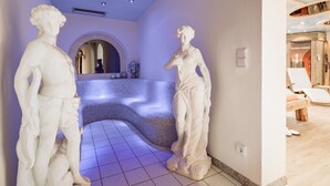 Ein Wellnessbereich mit Marmorstatuen, einer gebogenen Bank und einer Rezeption.