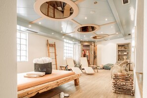 Ein Zimmer mit einem Holzbett, zwei Stühlen, einem kleinen Tisch und einem Holzstoß.