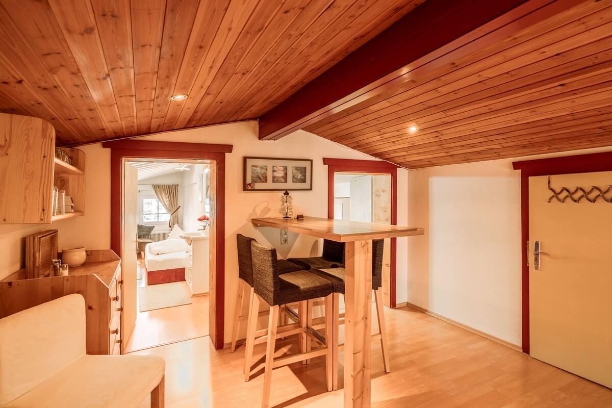 A wooden interior with a dining area, a kitchen, and a bedroom.