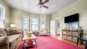 A living room with a red carpet, a ceiling fan, a TV, and a wooden cabinet. - 🐾5 Pleasant Street - Conveniently located in town, dog friendly (Rangeley)