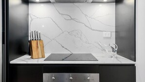 A modern kitchen with a marble backsplash, a wooden knife block, and a stainless steel range hood.