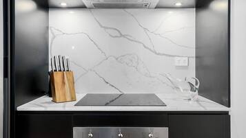 A modern kitchen with a marble backsplash, a wooden knife block, and a stainless steel range hood.