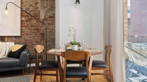 A dining area with a brick wall, a hanging light fixture, and a view of the outside balcony.