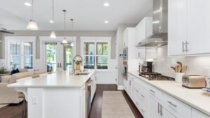 A modern kitchen with white cabinets, stainless steel appliances, and pendant lighting. - "Emerald Bliss" Luxury in NatureWalk 30A | Golf Cart + Bikes + Screened Porch (Santa Rosa Beach)
