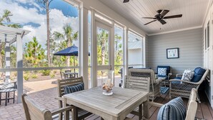A covered patio with outdoor furniture, a ceiling fan, and a view of the surrounding landscape. - "Emerald Bliss" Luxury in NatureWalk 30A | Golf Cart + Bikes + Screened Porch (Santa Rosa Beach)