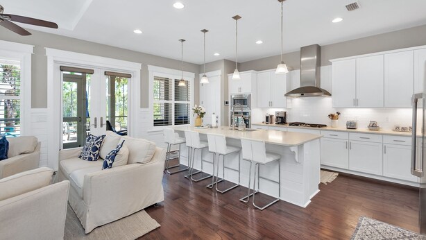 A modern kitchen with white cabinets, a central island with bar stools, a ceiling fan, and recessed lighting. - "Emerald Bliss" Luxury in NatureWalk 30A | Golf Cart + Bikes + Screened Porch (Santa Rosa Beach)