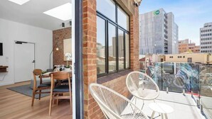 A modern interior with a dining area, a balcony with white chairs, and a view of the cityscape. - Sanctuary at Saddlers Where Rustic Meets Refined (Hobart)