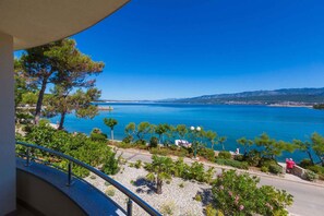 A balcony with a view of a coastal area, including a beach, trees, and a clear blue sky. - Holiday apartment mit Meerblick (Šilo)
