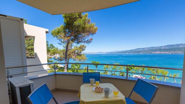 Ein Balkon mit Tisch für zwei Personen, mit Blick auf die Küste.