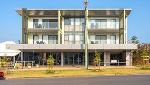A modern multi-story building with balconies, large windows, and a flat roof.