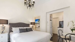 Ett hotellrum med en stor säng, en TV, ett skrivbord med en stol och en kristallkrona.