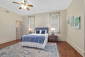 A bedroom with a bed, bedside lamps, a ceiling fan, and a window with blinds. - The Ray - 1st Floor - Walk to Downtown! (St. Augustine)