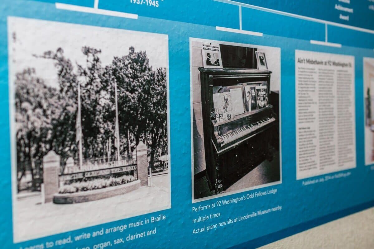 A historical timeline with black and white photographs, including a piano and a memorial.