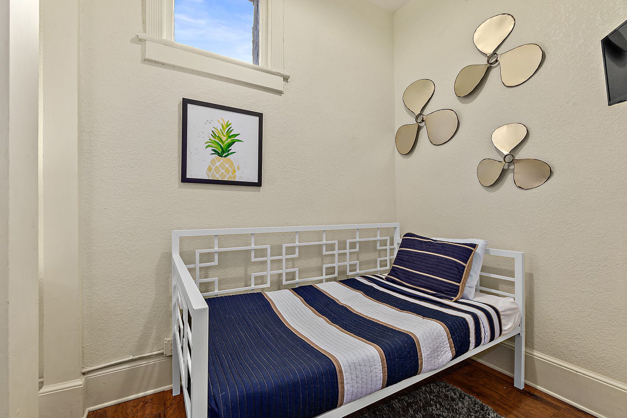 A bedroom with a bed, a framed picture, wall-mounted fans, and a window.