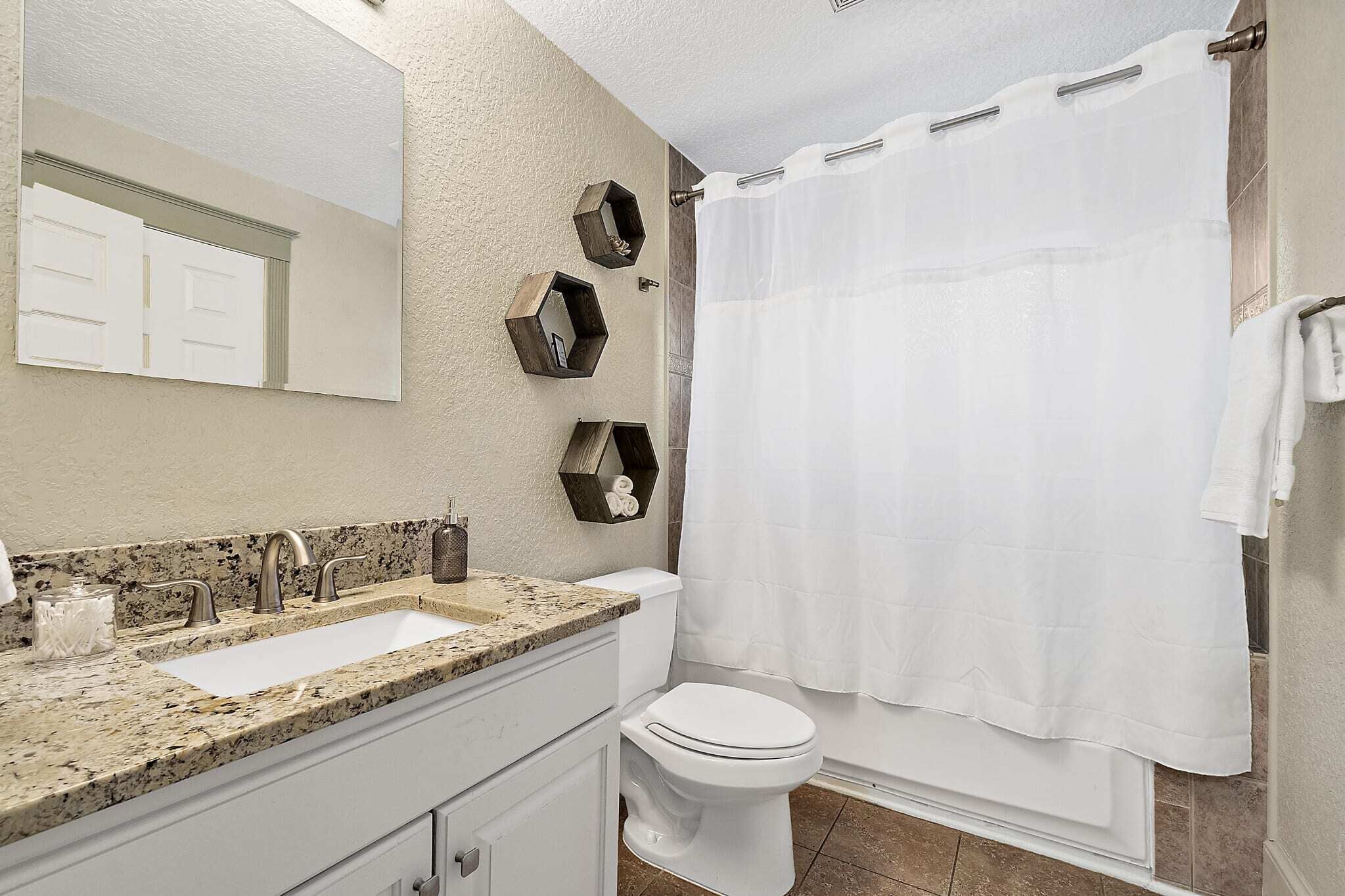 A bathroom with a white sink, two faucets, a toilet, and a shower curtain.