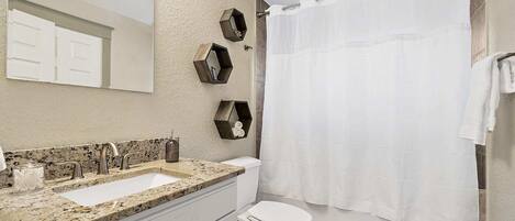 A bathroom with a white sink, two faucets, a toilet, and a shower curtain.