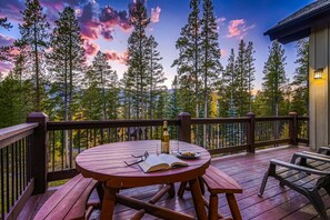A wooden deck with a round table, a bottle, and a book. - Horseshoe Lodge | VIP Shuttle | Hot Tub | Views! (Breckenridge)