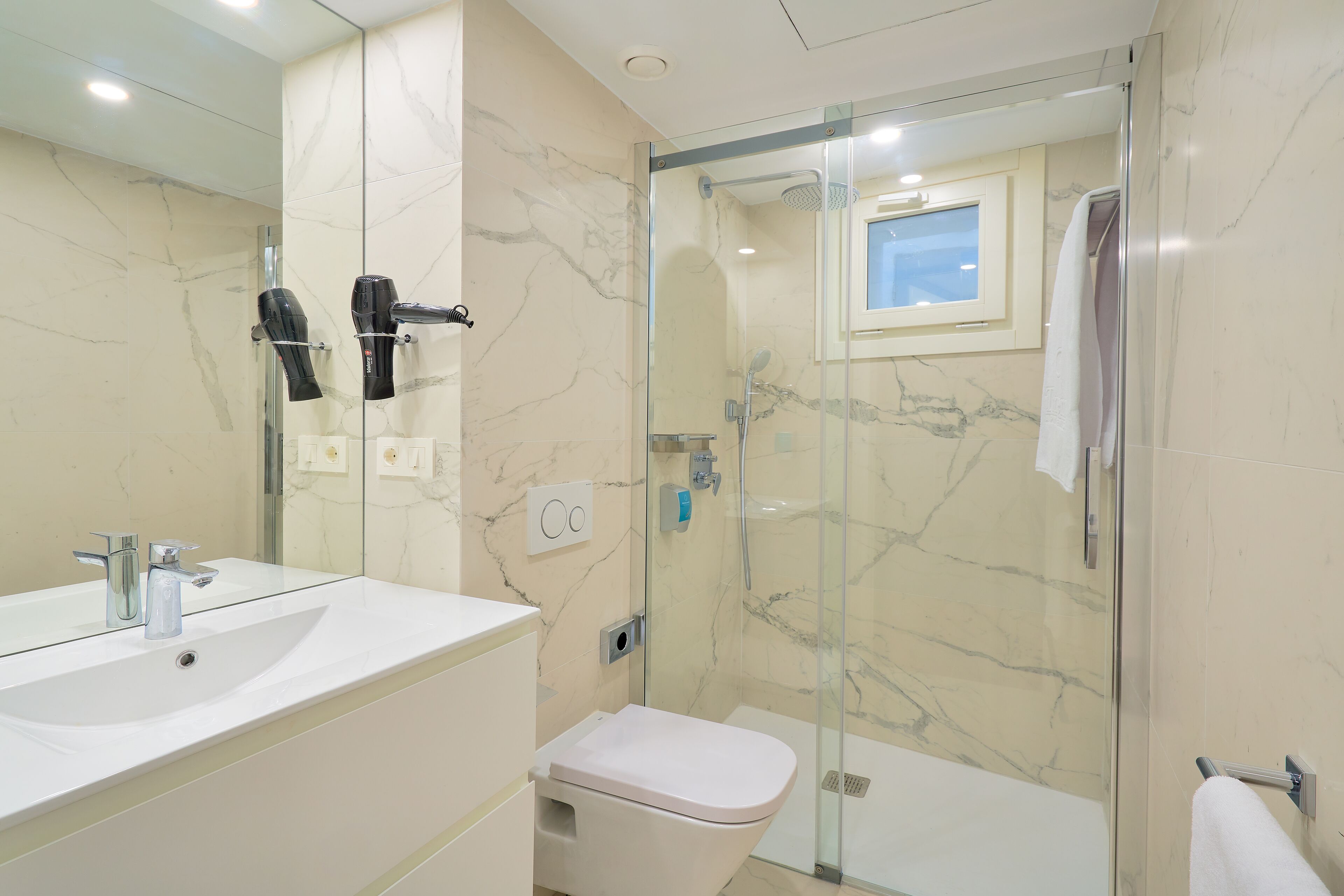 A modern bathroom with a glass-enclosed shower, a white sink, and a toilet.