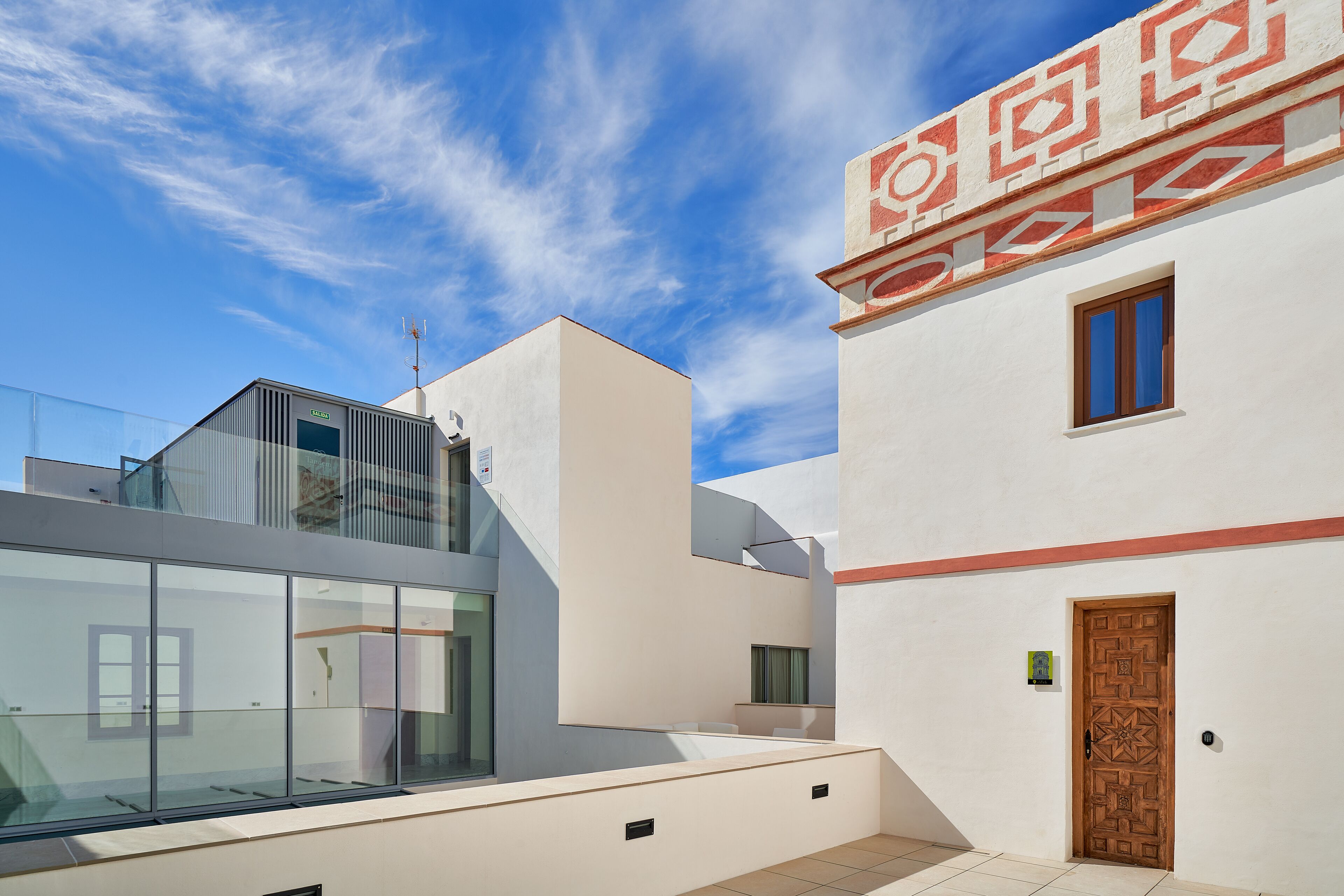 A modern building with a glass facade and a traditional wooden door.