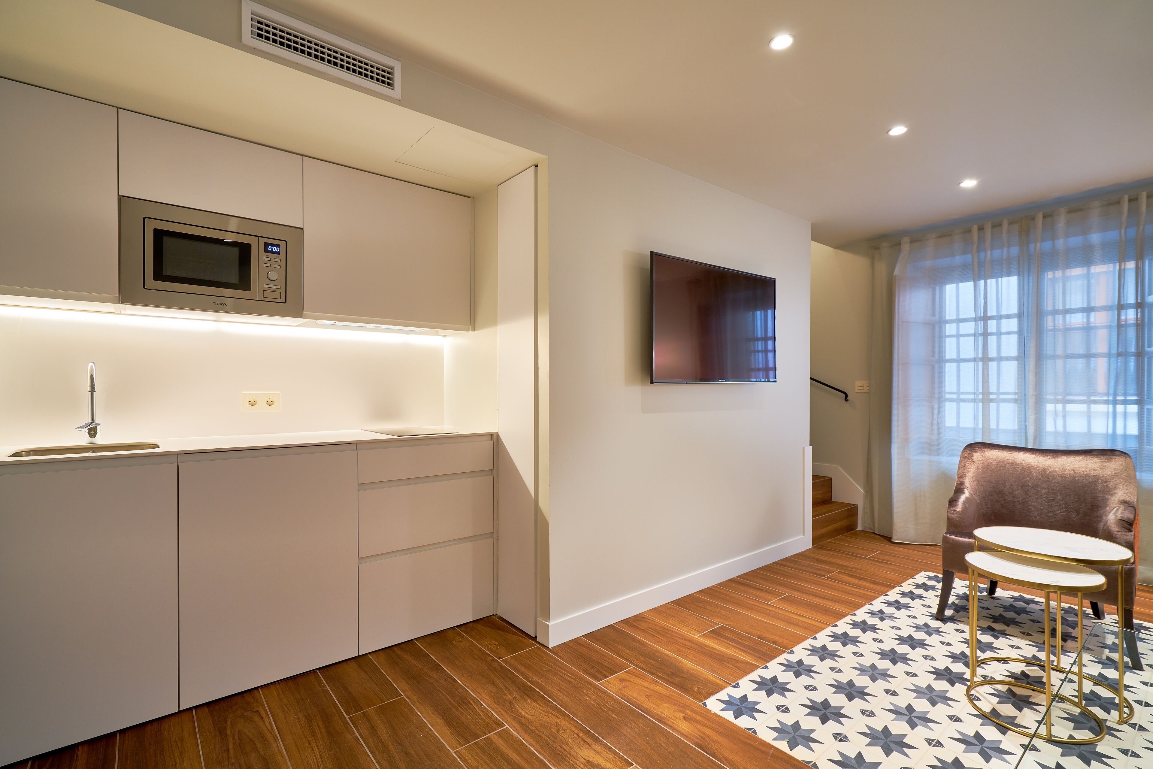 A modern kitchen with a microwave, built-in cabinets, and a TV mounted on the wall.
