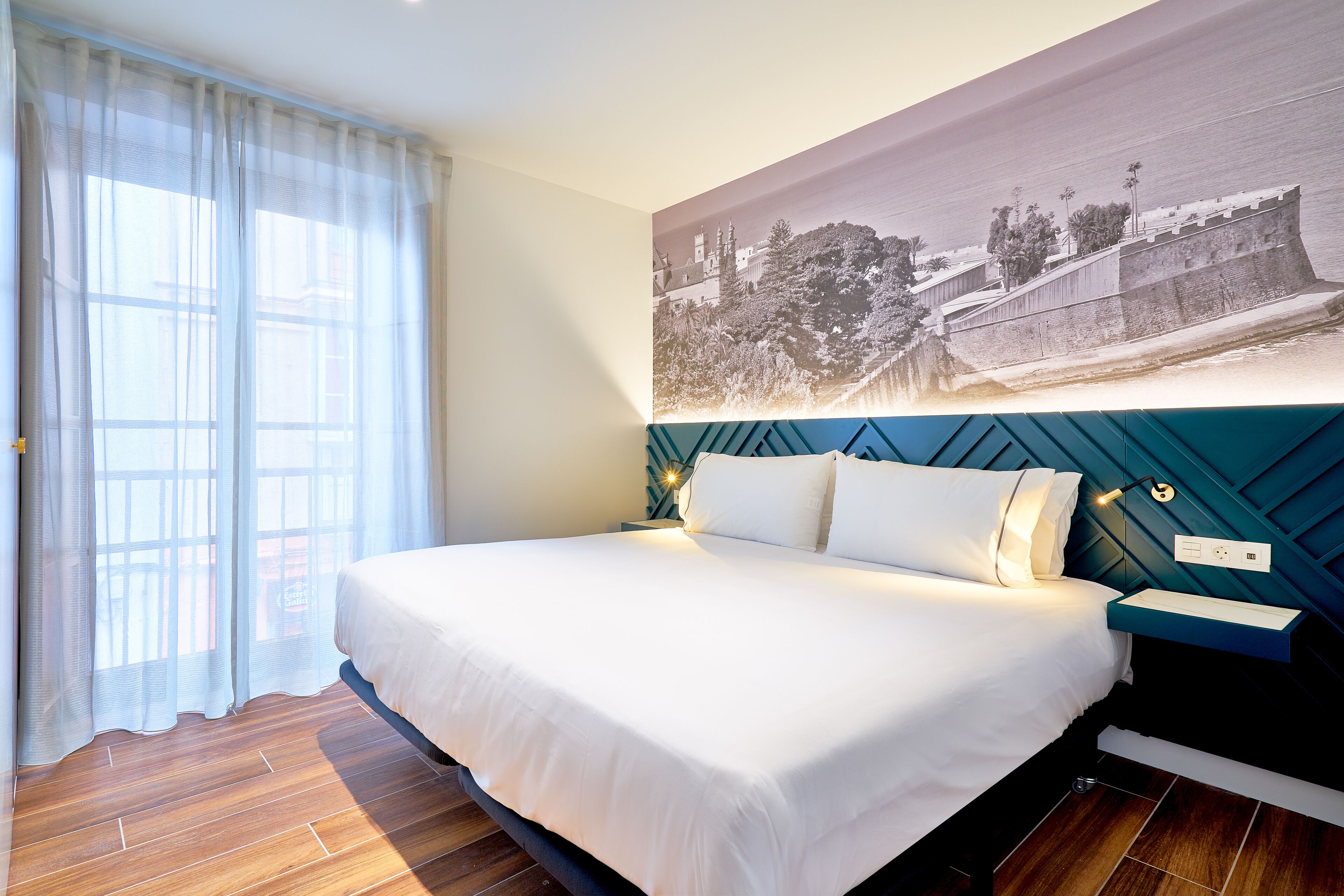 A hotel room with a large bed, a view of a coastal landscape, and a modern design.
