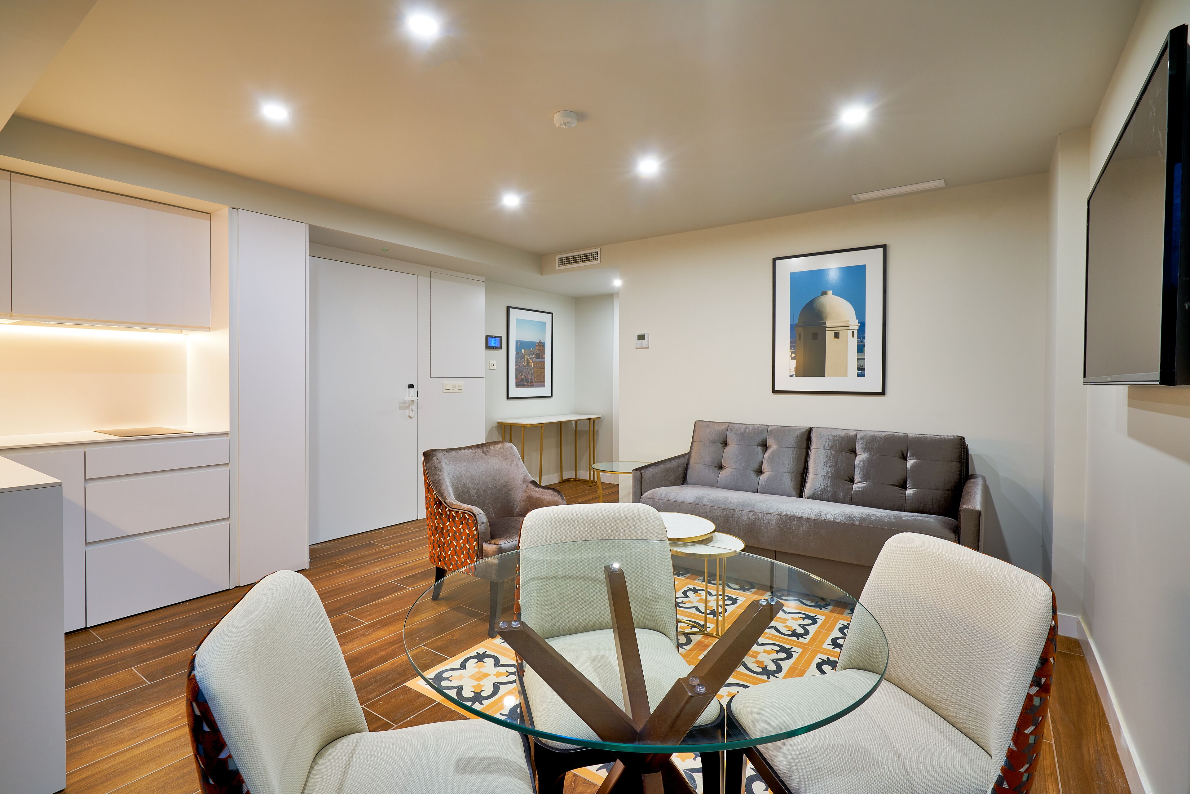 Una sala de estar moderna con una mesa de vidrio, dos sillones, un sofá y una mesa baja.