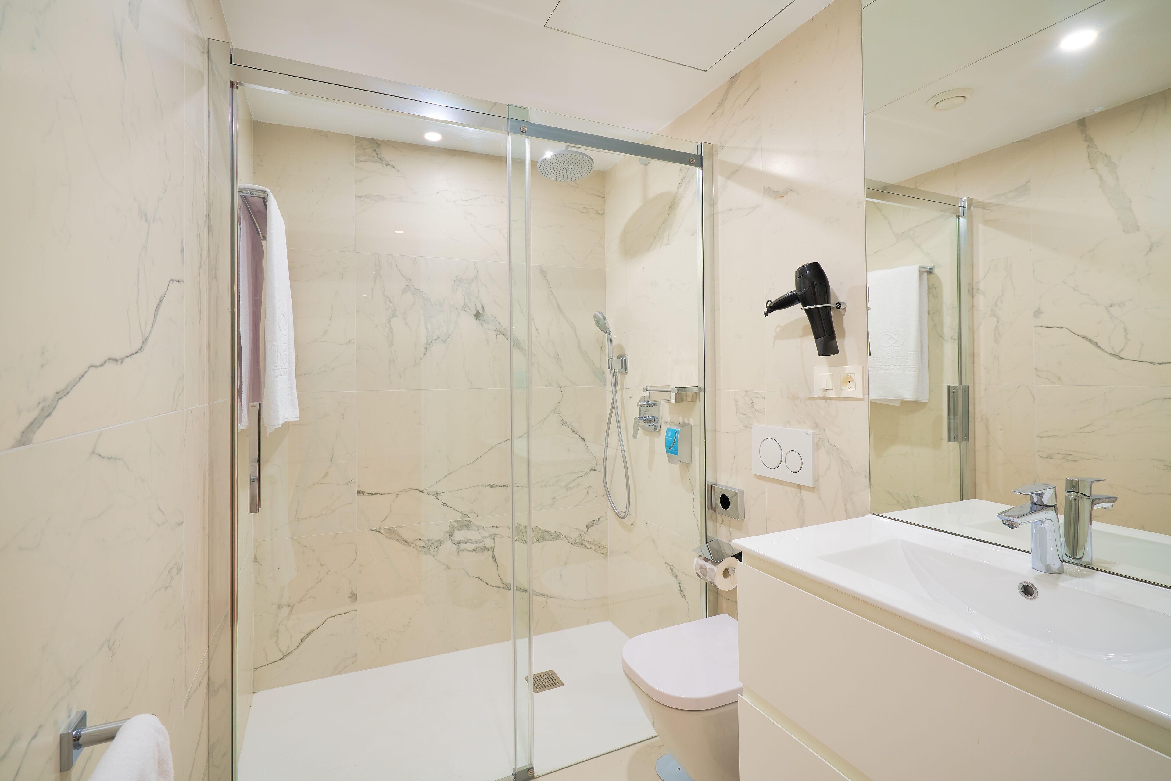 A modern bathroom with a glass-enclosed shower, a white sink, and a toilet.