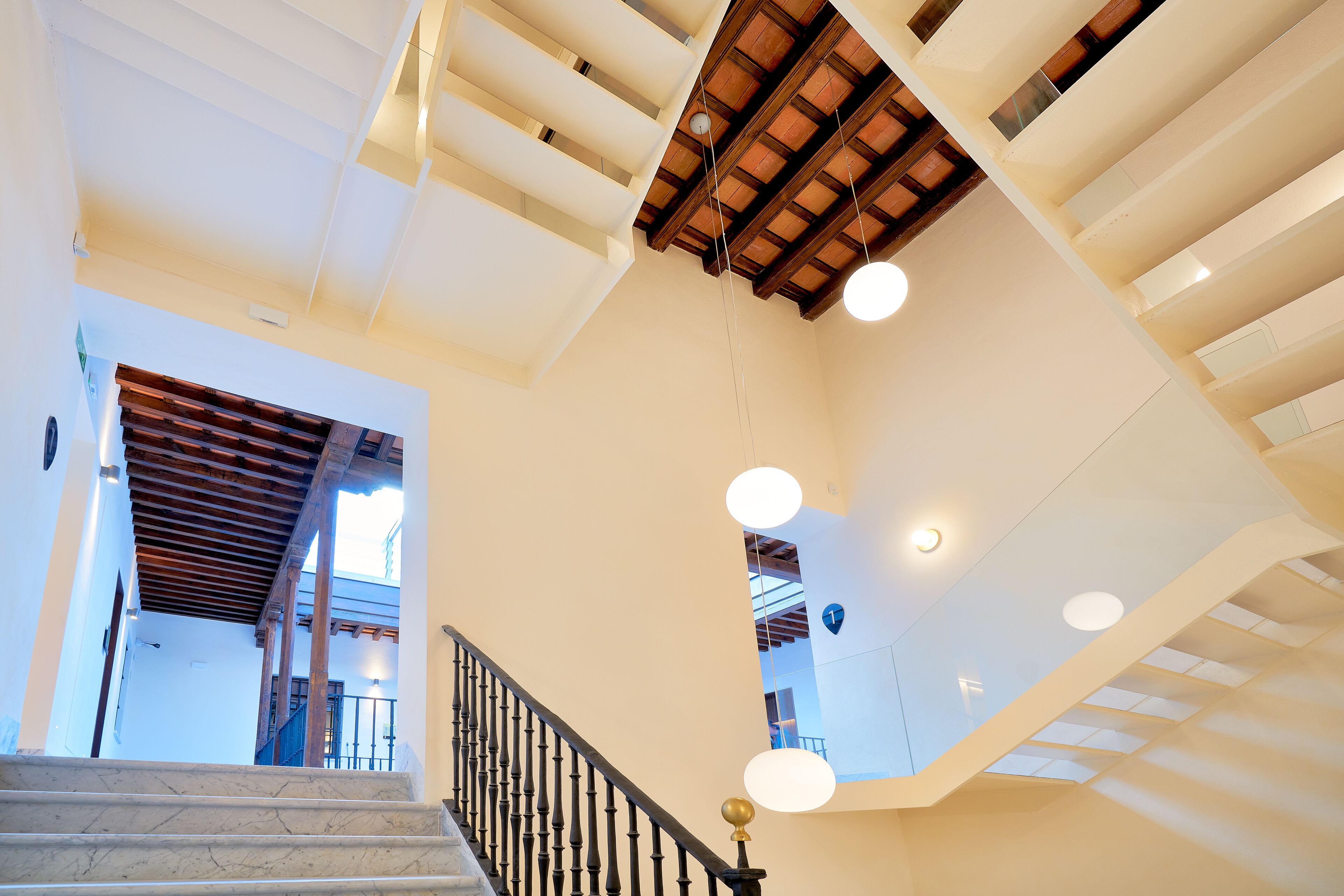 A staircase with a wooden ceiling and a black balustrade.