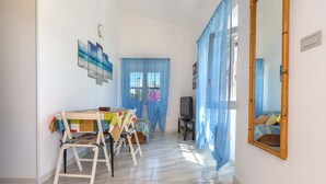 Una habitación con cama, televisor, mesa y sillas, y un cuadro en la pared.
