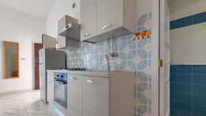 Una cocina con gabinetes de color claro, horno empotrado, estufa a gas y pileta de acero inoxidable.