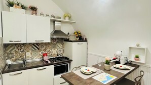 Una cocina compacta con armarios blancos, una estufa a gas y un comedor con mesa y sillas.