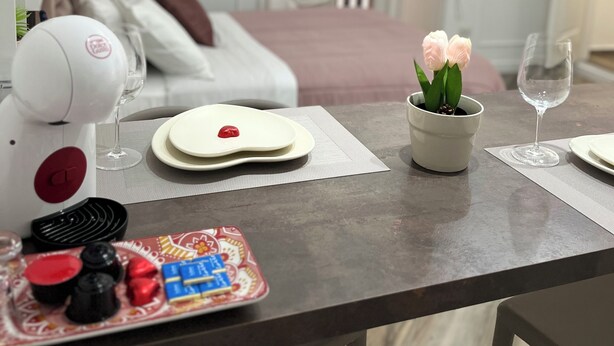 Una mesa de comedor con un plato de galletas, un vaso de agua y una pequeña planta en maceta.