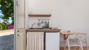Una cocina compacta con refrigerador integrado, un lavamanos pequeño y una encimera de madera.