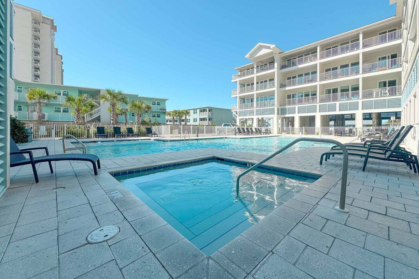 A swimming pool with lounge chairs, a manhole cover, and a multi-story building with balconies.