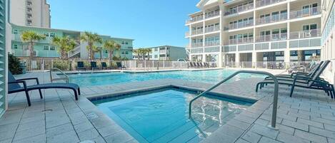 A swimming pool with lounge chairs, a manhole cover, and a multi-story building with balconies.